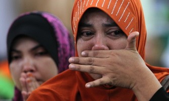 AFP - Relatives mourns next to coffins inside a mosque in Hulu Langat, Selangor on May 22, 2011.