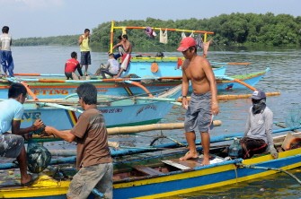 AFP - Photo taken on May 7, 2011 shows fishermen bringing in their catch as birds feed in the background at the Coastal Lagoons in Manila Bay.
