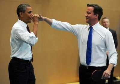 US President Barack Obama high-fives with British Prime Minister David Cameron as they play table tennis with students of the Globe Academy school in London