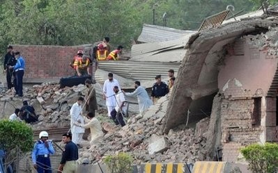 Pakistani security personnel and volunteers search for victims in the rubble of a destroyed police station following a suicide bomb attack in Peshawar on May 25, 2011.