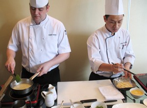 Caravelle chef Darren Watson (L) and his assistant Tran Thai Bao make a dish of spanner crab risotto, crispy squid and petit pois at Monday’s press briefing about the 2011 Australian Wine and Food Show. Watson will prepare a six-course meal for the event. (Photo: Minh Tuong)