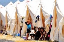 Syrian refugees sit in front of their tents at the Boynuyogun Turkish Red Crescent camp in the Altinozu