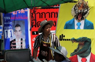 AFP - A Thai street food vendor stands amid electoral posters in Bangkok on June 28, 2011.