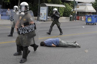 A demonstrator lies on the ground as riot police police disperse protestors who tried to block roads leading to the Greek Parliament during a 48-hour general strike in Athens on June 29, 2011.