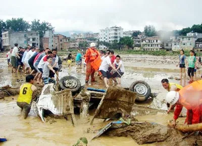 Người dân Quý Châu kéo chiếc xe tải dưới bùn lầy do bị lũ cuốn