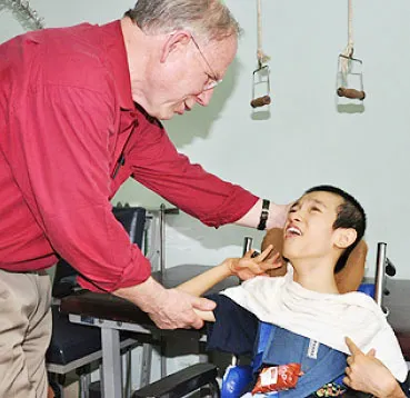 Tiến sĩ Charles Bailey, Giám đốc sáng kiến đặc biệt về chất độc da cam/dioxin của Quỹ Ford (của Mỹ) thăm em Nguyễn Văn Minh (14 tuổi), nạn nhân chất độc da cam hiện đang sống ở làng trẻ em Biên Hòa ngày 8-4-2011.