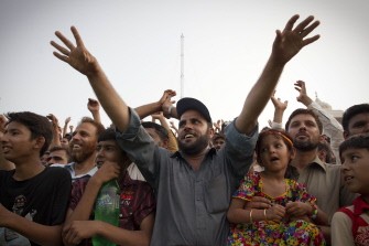 Pakistani spectators cheer during a daily ceremony to lower the flags of Pakistan and India at the Wagha border near Lahore on July 17, 2011.