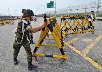 South Korean soldier remove a barricade for trucks carrying 300 tons of flour before crossing the inter-Korean border at a military checkpoint in Paju, north of Seoul, on July 26, 2011