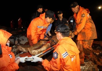 South Korean rescue members carry a victim after a landslide flattened an inn and three homes in Chuncheon, 80 kilometres east of Seoul, on July 27, 2011.