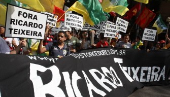 Demonstrators hold signs against the president of the Brazilian Football Confederation, Ricardo Texeira, as they march on July 30, 2011, to protest against the investments done to build stadiums for the 2014 FIFA World Cup in Rio de Janeiro