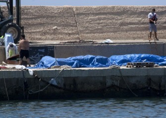 Volunteers close coffins with the dead immigrants found in a boat by Italian coast guards that arrived on the southern Italian island of Lampedusa on August 1, 2011
