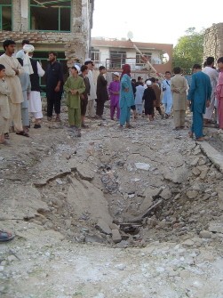 Afghan locals stand at the site of a suicide car bomb at the entrance to the office of a private security company in Kunduz on August 2, 2011