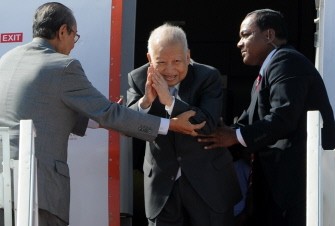 AFP - Cambodian former King Norodom Sihanouk (C) gestures to people as Cambodian Minister of the Royal palace Kong Sam Ol (L) assists him at the Phnom Penh International Airport on August 3, 2011