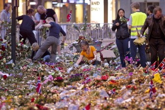 AFP - Workers remove flowers and candles, placed in front of Oslo Cathedral in memory of the victims of the July 22 attacks, early on August 3, 2011