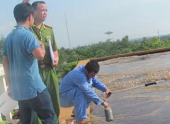 Police official collects samples of wastewater from the Sonadezi Company reservoir (Photo: Tuoi Tre)
