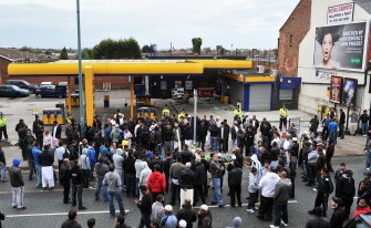 Residents stand at the crime scene where Haroon Jahan and two other Asian men were hit by a car and killed in the early hours Wednesday in Birmingham, central England, on August 10, 2011.