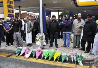 AFP - Residents stand by flowers laid at the crime scene where Haroon Jahan and two other Asian men were hit by a car and killed in the early hours Wednesday in Birmingham, central England, on August 10, 2011