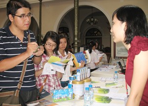 A staff member from the Friesland Campina Vietnam recruitment department (R) provides students with her company’s employment information at the training camp August 13, 2011 (Photo: Minh Tuong)