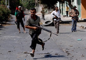 AFP - A Libyan rebel fighter dashes over a street to evade sniper fire in Zawiya, some 40 kms west of Tripoli on August 19, 2011