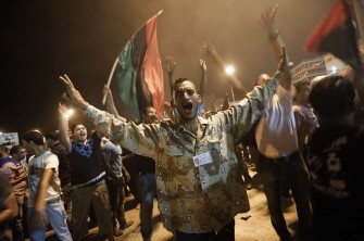 AFP- Libyans listen to the arrest of Kadhafi's son Saif al-islam and the partial fall of Tripoli on August 21, 2011 in Benghazi, Libya
