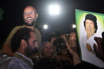 AFP- Saif al-Islam Kadhafi, son of Libyan leader Moamer Kadhafi (portrait), is surrounded by supporters and journalists at his father's residential complex in the capital Tripoli in the early hours of August 23, 2011
