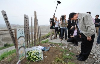 Thailand's fugitive ex-prime minister Thaksin Shinawatra (R) bows to offer condolences to the victims of the devastating March 11 earthquake and tsunami at a memorial placed along the tsunami-hit coast in Natori, Miyagi prefecture on August 25, 2011