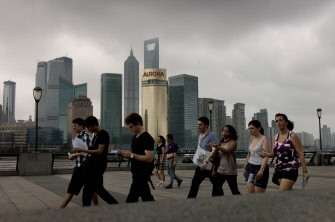AFP - Tourists walk along Bund promenade past the city's skyline financial district in Shanghai on August 30, 2011. Tropical Storm Nanmadol headed towards China August 30, forcing tens of thousands of boats back to harbour.