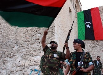 NTC fighters waving the newly adopted Libyan flag, as women (unseen) gather in Marty's Square in the capital Tripoli during a rally on the third and last day of Eid al-Fitr which marks the end of the Muslim holy month of Ramadan, on September 2, 2011.