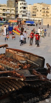Libyan children walk past destroyed military tanks in a playground in the city of Misrata on September 4, 2011.