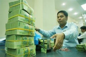 A cash teller counts a pile of cash at a HCMC-based bank. The State Bank of Vietnam announces to retain a tight and cautious monetary policy to fight against inflation for the rest of the year (Photo: Minh Tri)