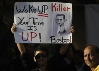 A press photographer (R) stands next to a Lebanese man carrying a sign calling on Syrian President Bashar al-Assad to step down during a rally in support of Syria's ongoing anti-regime uprising in downtown Beirut on September 8, 2011