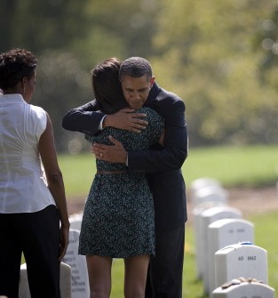 US President Barack Obama and First Lady Michelle Obama (L) visit with a family at a gravesite in section 60 at Arlington National Cemetery on September 10, 2011.