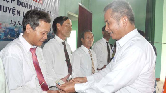 Vietnam General Confederation of Labor chairman Dang Ngoc Tung (R) presents membership cards to Ly Son fishermen (Photo: An Ninh Thu Do newspaper)