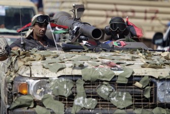 Anti-Moamer Kadhafi fighters drive their armoured vehicle into the desert city of Bani Walid, southeast of Tripoli on September 16, 2011, as National Transitional Council (NTC) forces thrust deep into the area, one of two of fugitive Moamer Kadhafi's few remaining bastions.