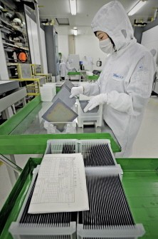 This file picture taken on November 28, 2009 shows a masked worker in a lab coat sorting silicon wafers at the manufacturing centre of solar cell maker Trina Solar in Changzhou.