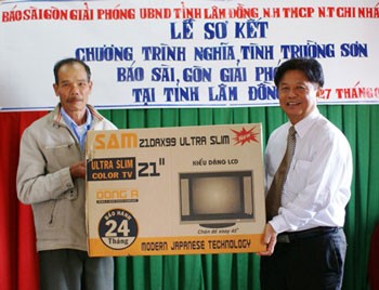 Sai Gon Giai Phong Editor-in-chief Tran The Tuyen (R) hands out a present to Nguyen Van in Don Duong District. (Photo: Sggp)