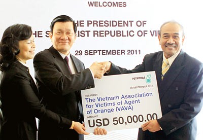 Vietnamese President Truong Tan Sang (2nd, L) receives a token check of US$50,000 donated by Petronas for Vietnamese Agent Orange victims in Kuala Lumpur September 29, 2011 (Photo: Vietnam News Agency)