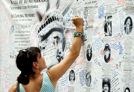 Một người phụ nữ viết thông điệp trên bức tường tưởng nhớ những nạn nhân của cuộc khủng bố ngày 11-9-2001 gần trung tâm thương mại thế giới hôm 10-9-2011