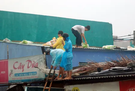 Dân cư ven biển trên đường Nguyễn Tất Thành (Đà Nẵng) dùng bao cát chèn mái tôn vào sáng 26-9. Ảnh: Nguyễn Hùng