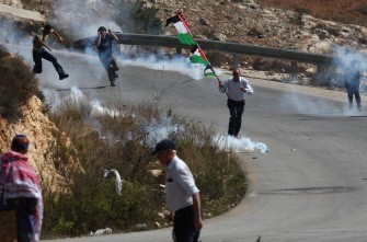 Protesters run amidst tear gas smoke as Israeli forces clash with Palestinian youths following a weekly demonstration against Israeli settlement expansion, in the West Bank village of Nabi Saleh, near the Jewish settlement of Halamish on September 30, 2011