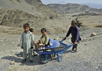 Afghan boys look at US army soldiers from HHB 3-7 Field Artillery Regiment 3rd Bct 25th ID patrol during their mission in Turkham Nangarhar, bordering Pakistan, on September 30, 2011.