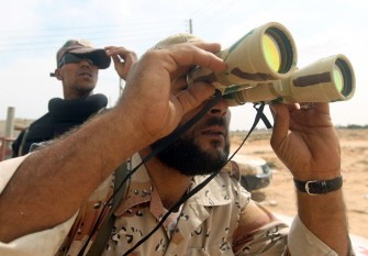 A National Transitional Council fighter uses binoculars as they take position on the eastern front line of Sirte on October 2, 2011.