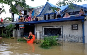 A family sits marooned on their rooftop after Typhoon Nalgae flooded the town of Calumpit, an agricultural town about two hours north of the capital Manila, on October 2, 2011.