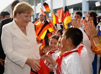 AFP photo - Visiting German Chancellor Angela Merkel (L) is greeted by children as she arrives to attend the grand opening of the B. Braun Vietnam medical plant on the outskirts of Hanoi on October 11, 2011.