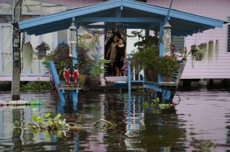 Thai residents stand at their doorstep and watch floodwaters, near the Chaopraya river in Bangkok, on October 14, 2011.