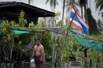 A Thai man stand infront of his flooded house near the Chaopraya river in Bangkok on October 14, 2011.