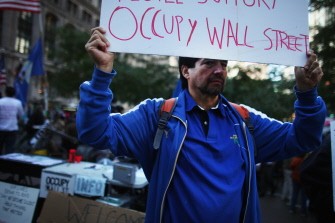 AFP - A man holds a sign on the edge of Zuccotti Park in the Financial District where Occupy Wall Street protesters are living on October 17, 2011 in New York City.