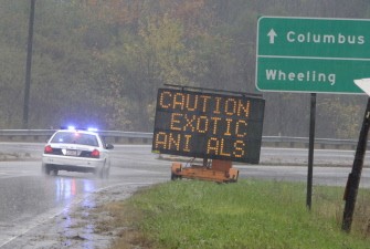 AFP - An Ohio State Highway Patrol officer drives past a sign warning of the exotic animals on the loose from a wildlife preserve October 19, 2011 in Zanesville, Ohio.