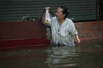 AFP - An elderly woman walks with a cane in floodwaters as water levels rose after a mud and sandbag wall collapsed in Bang Bua Thong in Nonthaburi province, suburban Bangkok, on October 19, 2011.