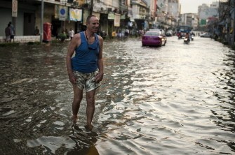 A tourist walks in floodwaters near the Chao Praya river in Bangkok, on October 24, 2011